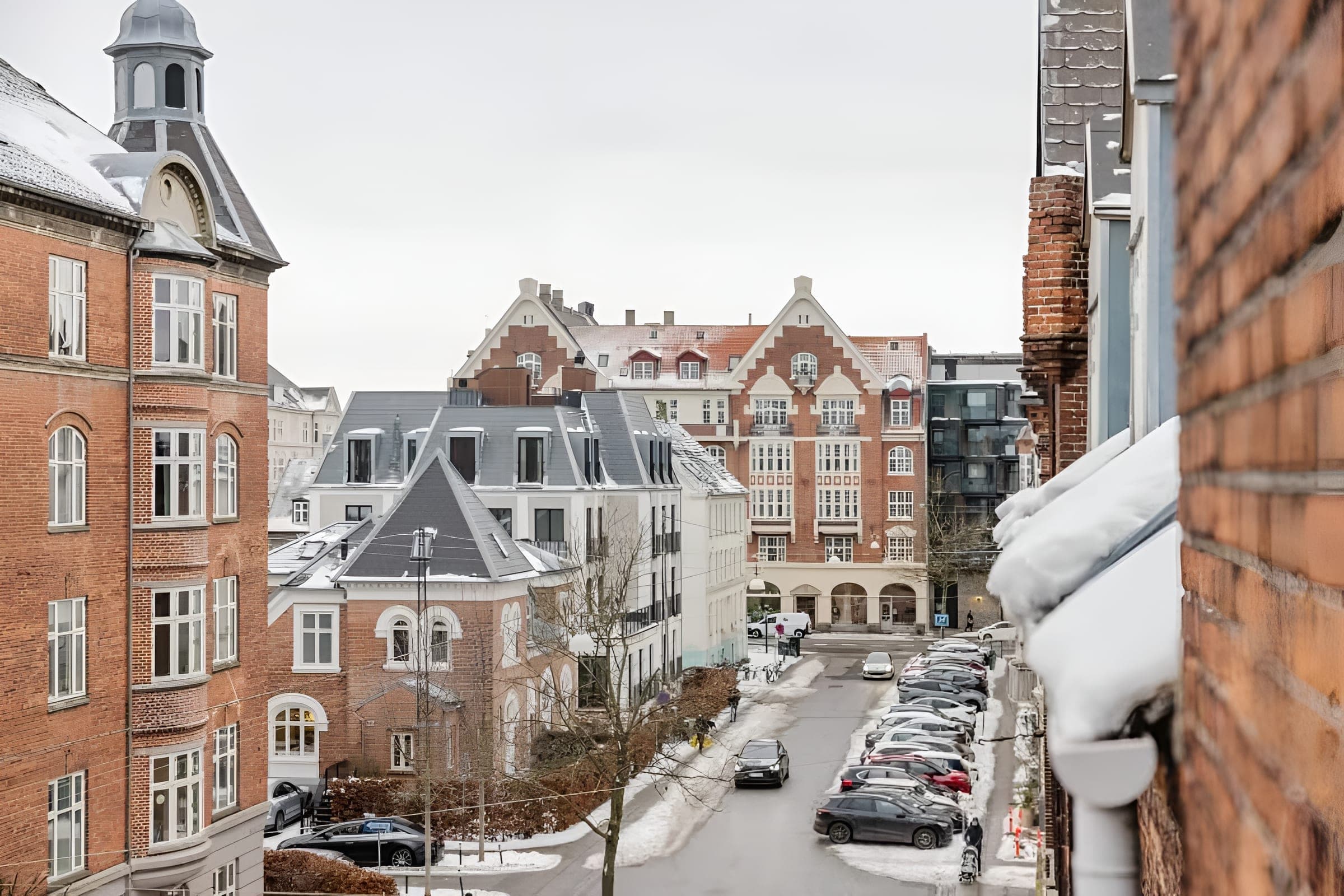 Snowy Frederiksberg street and brick buildings viewed from a window